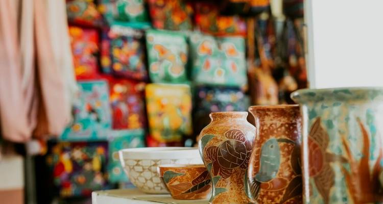 Colorful handcrafted pottery displayed indoors with vibrant painted backgrounds.
