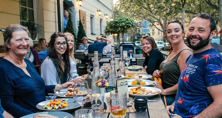 Group of people dining at an outdoor restaurant table.