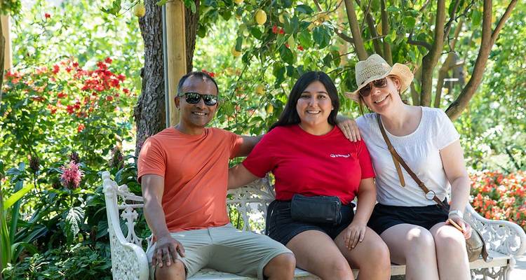 Three people sitting on a garden bench.