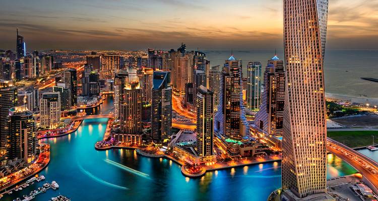 Vue aérienne vivante du soir à Marina Dubaï avec voies navigables néon et gratte-ciel lumineux.