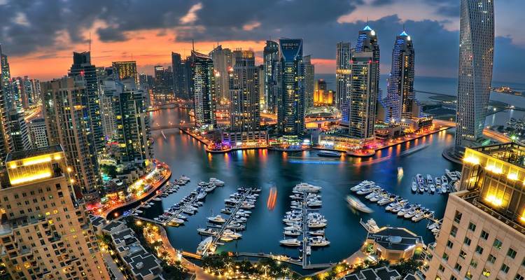 Schemering uitzicht over Dubai Marina met verlichte wolkenkrabbers en luxe jachten langs de waterwegen.
