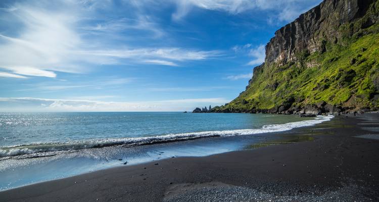 Bergachtige kustlijn met een zwart zandstrand in IJsland.