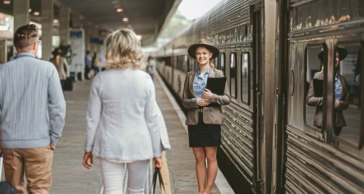 Des gens marchant sur un quai de train avec un contrôleur souriant.
