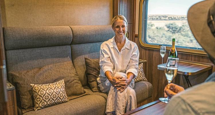 Une femme qui se détend dans un compartiment de train avec une boisson.