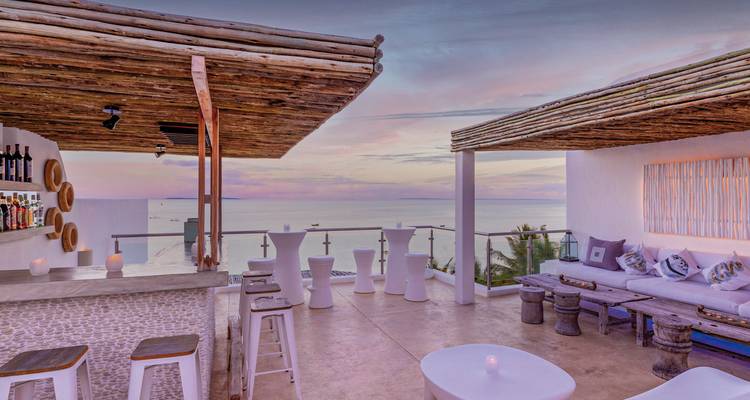 Rooftop terrace overlooking the ocean at sunset.