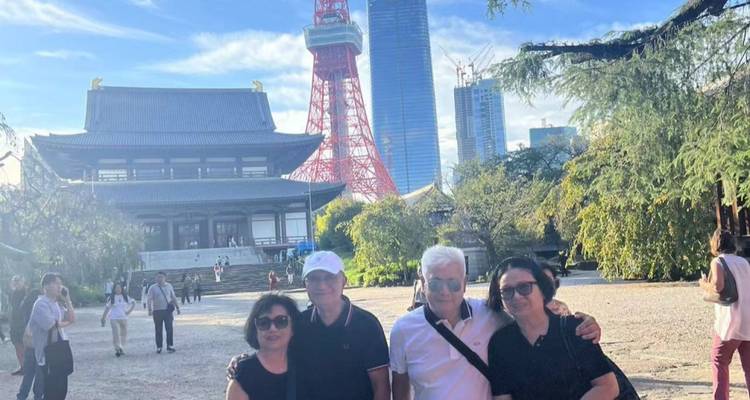 Group of people in front of Tokyo Tower and a traditional temple.