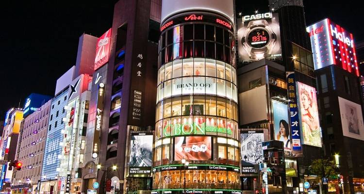 Lebendiges Einkaufsviertel in einer Stadt bei Nacht.