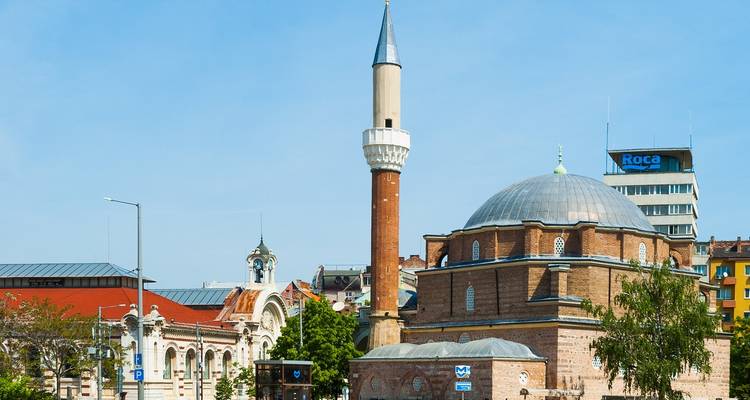 Vue d'une mosquée avec un minaret élevé dans un cadre urbain.