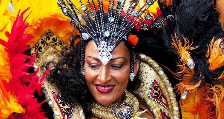 Een glimlachende carnavalsartiest in schitterende veren en juwelen poseert voor de camera.