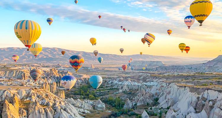 Montgolfières au-dessus de formations rocheuses au lever du soleil.