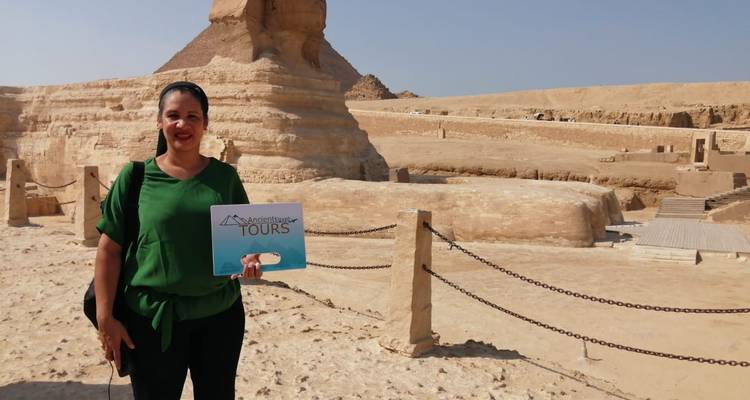 Vrouw die een toeristenbord vasthoudt met de Sfinx op de achtergrond.
