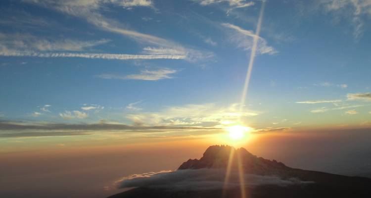 Sonnenuntergang an einem Berggipfel mit einer dramatischen Skyline.