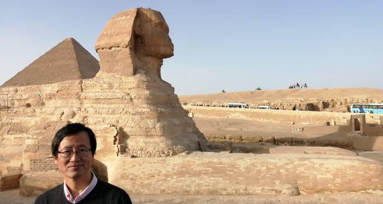 Man poseert met de Sfinx en piramide op de achtergrond.