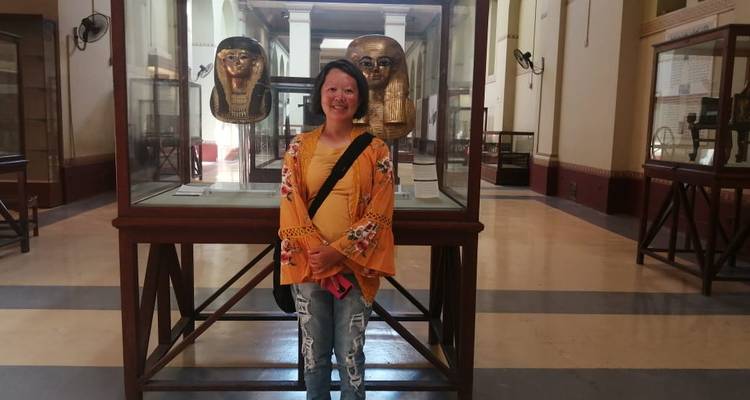 Vrouw die glimlacht voor oude artefacten in een museum.