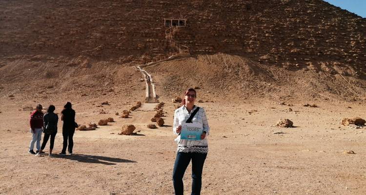 Toerist die een bord vasthoudt voor een grote woestijnheuvel.
