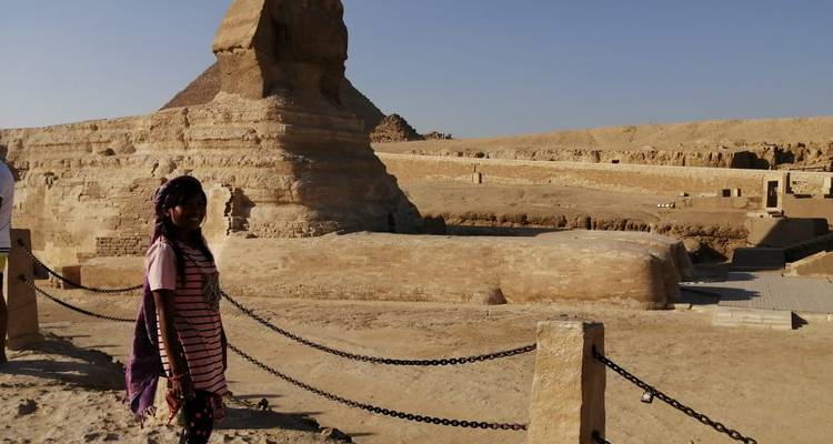 Persoon die bij de Sfinx staat met uitzicht op de woestijn in de open lucht.