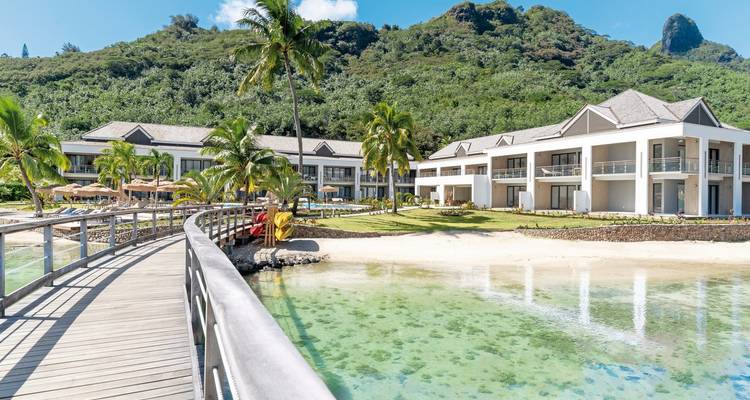 Complexe de luxe au bord de l'eau avec palmiers et vues sur les montagnes.