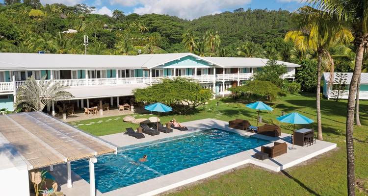 Complexe hôtelier avec piscine entouré d'un paysage tropical.