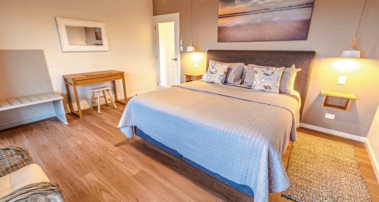 Intérieur de chambre douillet avec œuvres d'art de plage encadrées.