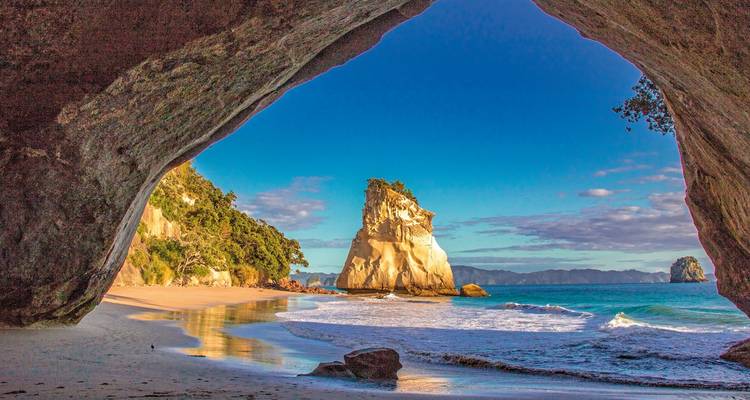 View from inside a cave to a coastal beach scene.