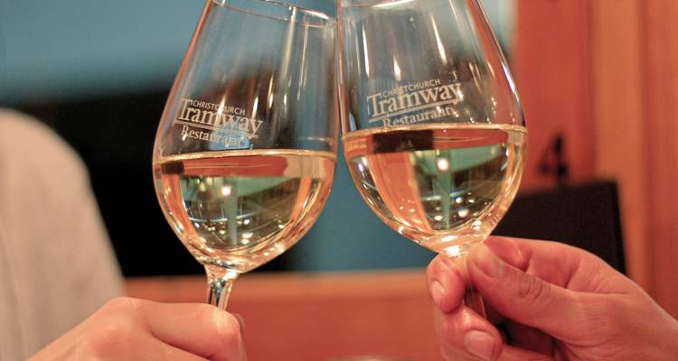 Two glasses of white wine clinking together.