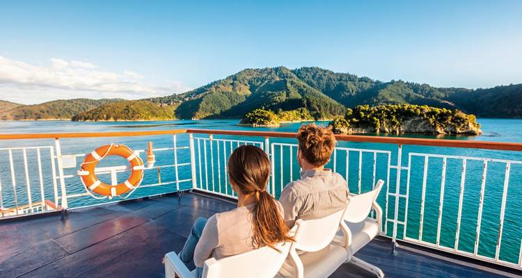 Two people on a boat enjoying a scenic view of the coastline.