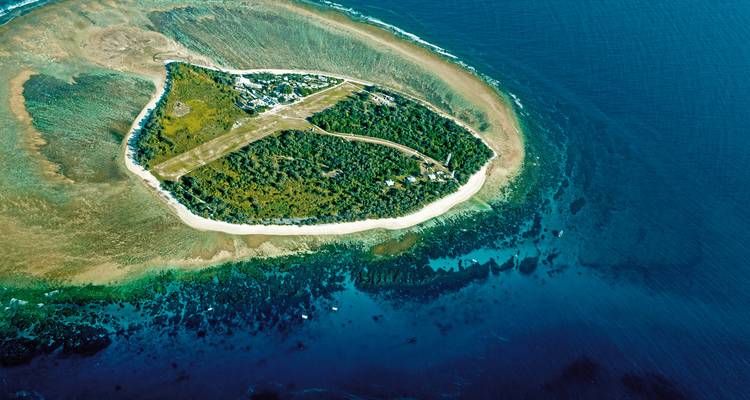 Arial view of an island with a runway surrounded by ocean.