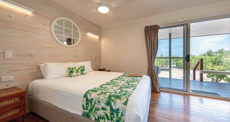 Interior of a hotel room with a bed and balcony view.