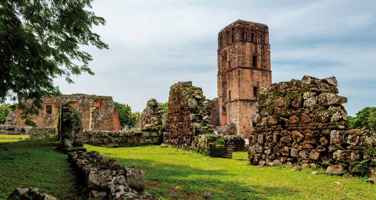 Old stone ruins with a tall tower and grassy surroundings.