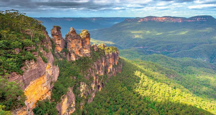 Vue panoramique de la formation rocheuse des Three Sisters dans un paysage luxuriant.