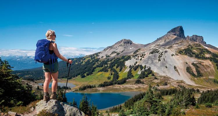 A hiker overlooking a mountainous landscape with a lake.