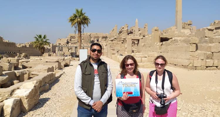 Drie toeristen met een tourbord voor oude ruïnes.