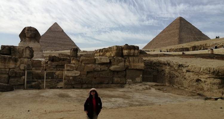 Een persoon voor de Sfinx en Piramides onder een bewolkte hemel.