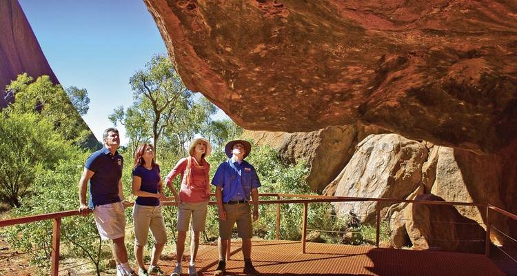 Group of visitors with a guide at the base of a large rock formation.