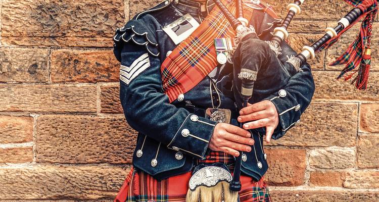 Close-up of a person in traditional Scottish attire playing bagpipes.