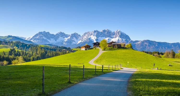 Route menant à des maisons avec un panorama montagneux pittoresque en arrière-plan.