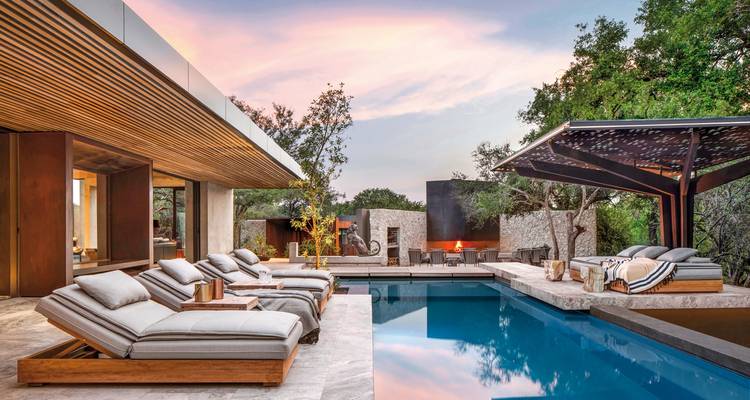 Zone piscine de luxe avec chaises longues rembourrées et une cheminée.
