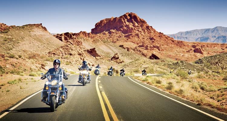 Group of motorcyclists traveling on a scenic road in the desert.