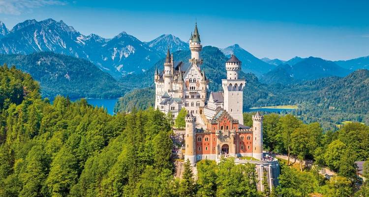 Neuschwanstein Castle surrounded by forested mountains.