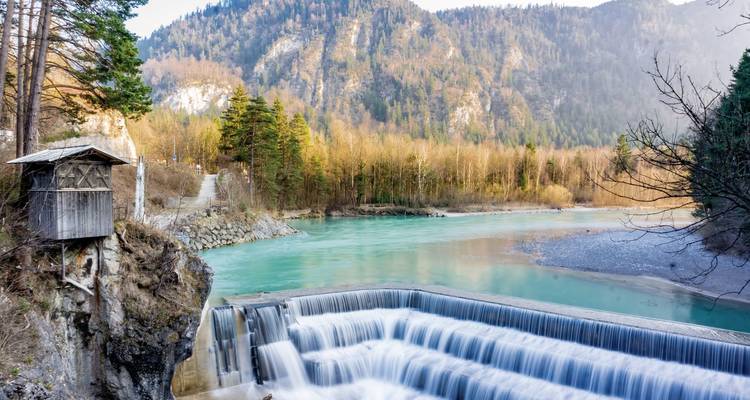 Small waterfall with turquoise water surrounded by mountains.