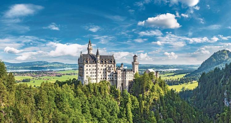 Neuschwanstein Castle on a cliff with wide landscape view.