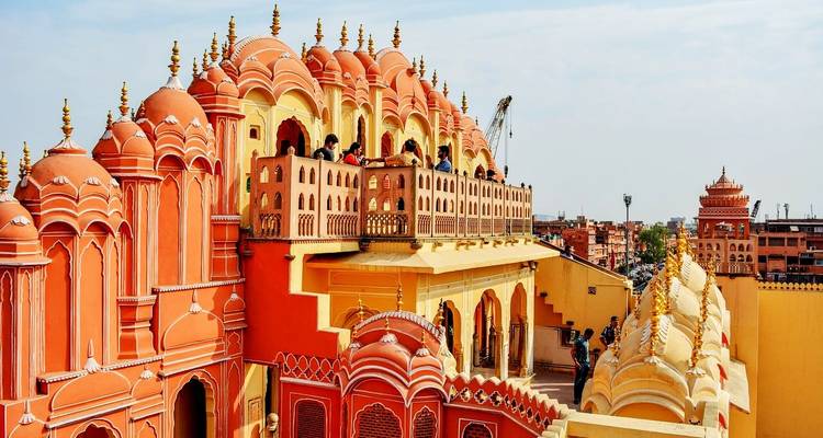 Des touristes sur un balcon d'un palais rose historique.