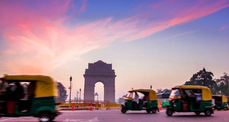 India Gate met levendige lucht en snel bewegende tuk-tuks in New Delhi.