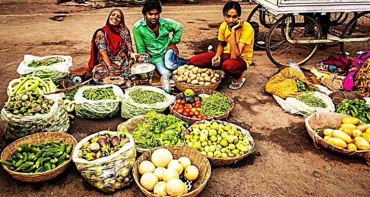 Straatmarkt met verkopers die verse fruit en groenten verkopen.