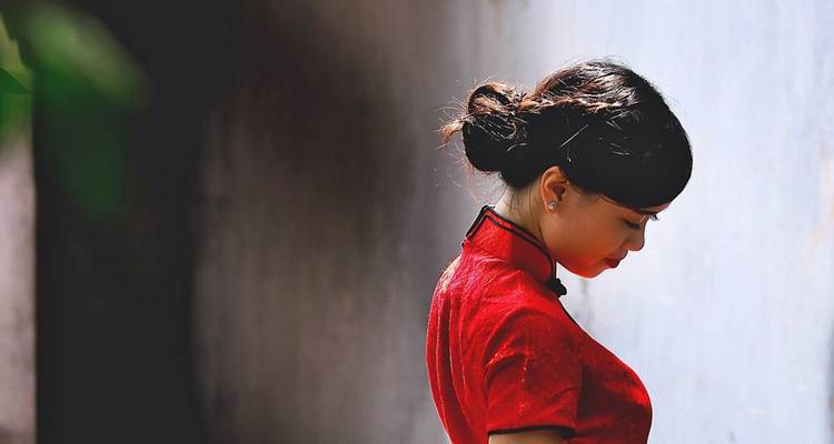 Porträt einer Frau in traditioneller Kleidung vor einer Wand.