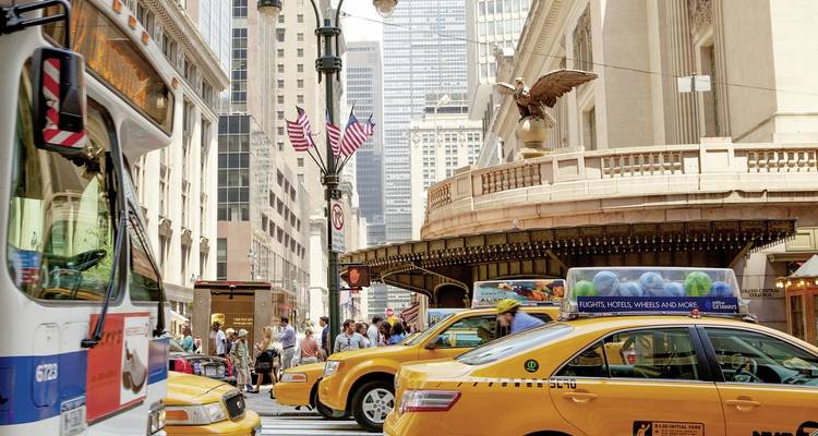 Belebte Stadtkreuzung mit Taxis und Wolkenkratzern.