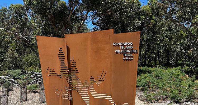 Un letrero de escultura de metal para el Sendero Silvestre de la Isla Canguro rodeado de árboles.