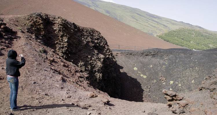 Personne prenant des photos sur un site volcanique.