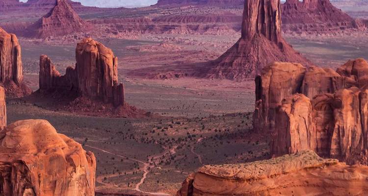 Los peñascos y mesetas de arenisca imponentes del Valle de los Monumentos se alzan desde un vasto desierto rojo bajo un cielo despejado