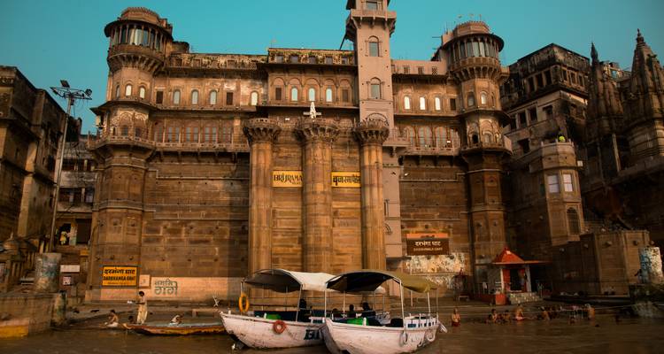 Boats on a river in front of a grand building.